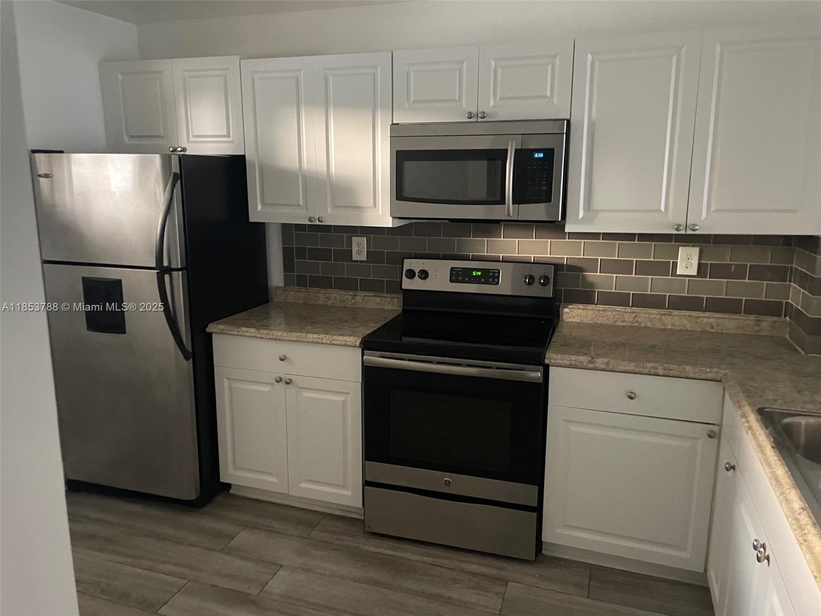 1075 Riverside Drive, Unit 203 Coral Springs, FL 33071 - Photo 2 of 9 a kitchen with stainless steel appliances a stove microwave and refrigerator