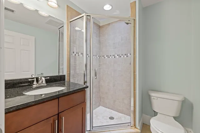 a bathroom with a granite countertop sink toilet and shower