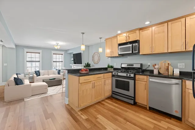 a kitchen with stainless steel appliances granite countertop a stove a sink dishwasher and a microwave oven with white cabinets