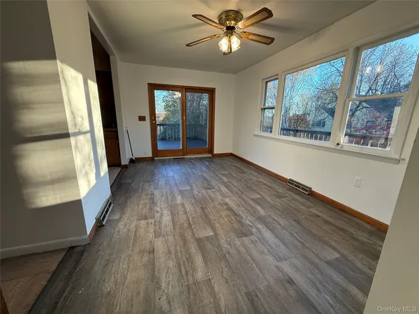 a view of empty room with wooden floor and fan