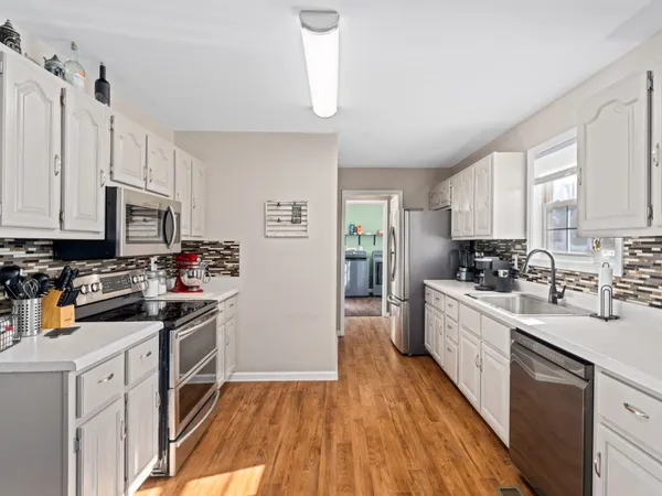 a kitchen with stainless steel appliances granite countertop a stove top oven a sink dishwasher and a refrigerator with wooden floor