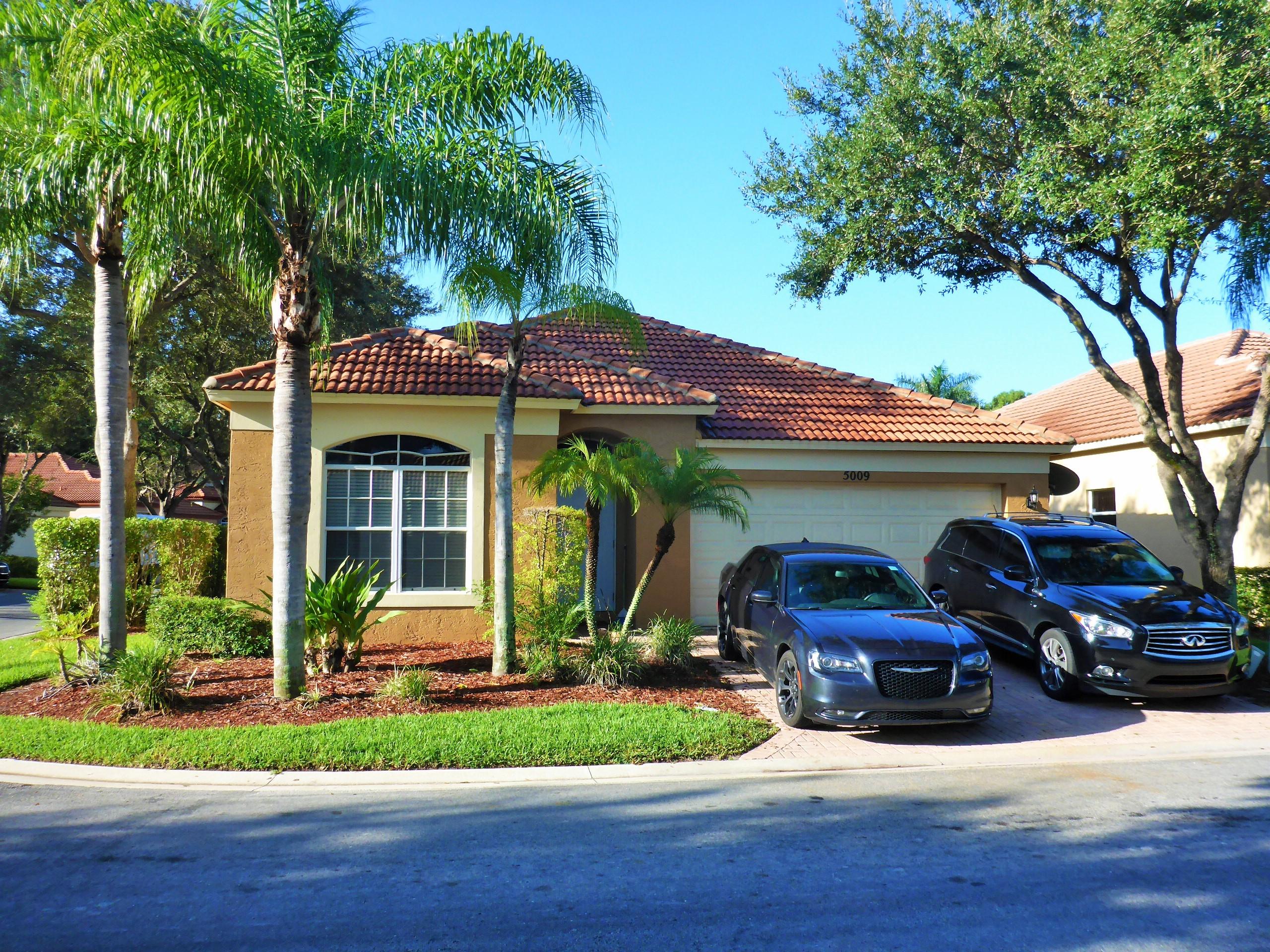 5009 Elpine Way Riviera Beach, FL 33418 - Photo 1 of 41 a front view of a house with garden and trees