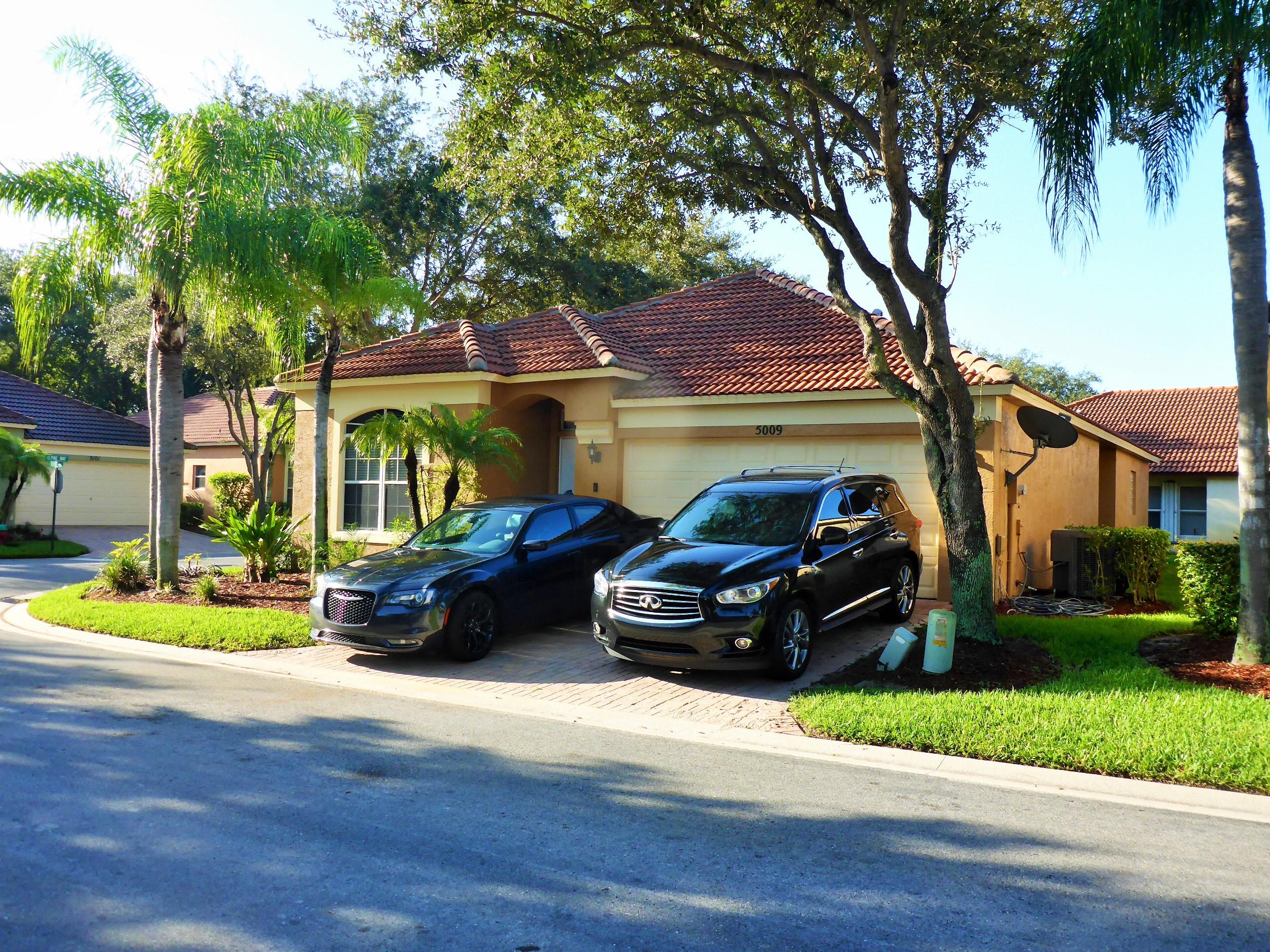 5009 Elpine Way Riviera Beach, FL 33418 - Photo 2 of 41 a front view of a house with a garden and trees