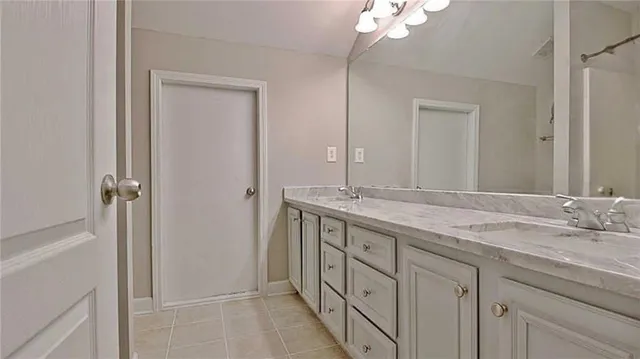 a bathroom with a granite countertop double vanity sink and a mirror