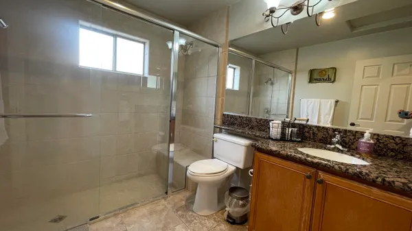 a bathroom with a granite countertop sink a toilet and shower
