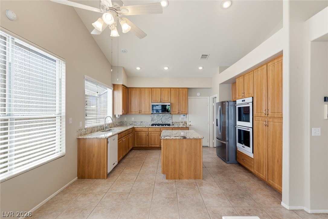 High vaulted ceilings and tile flooring enhance this functional kitchen layout with stone countertops.