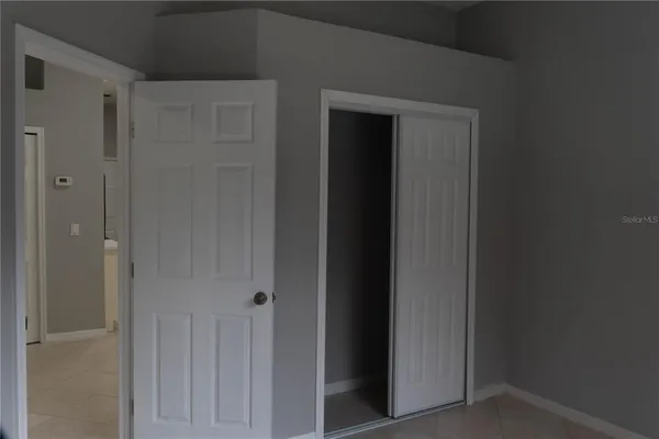 a view of an empty room with wooden floor and closet