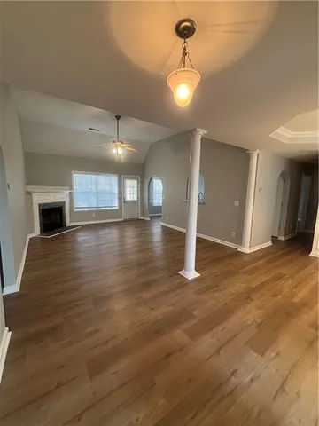 an empty room with wooden floor fire place and windows