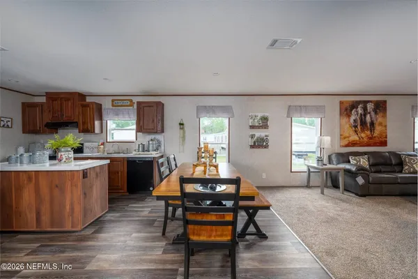 a living room with furniture a rug kitchen view and a table