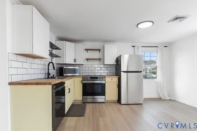 a kitchen with a sink a refrigerator and white cabinets