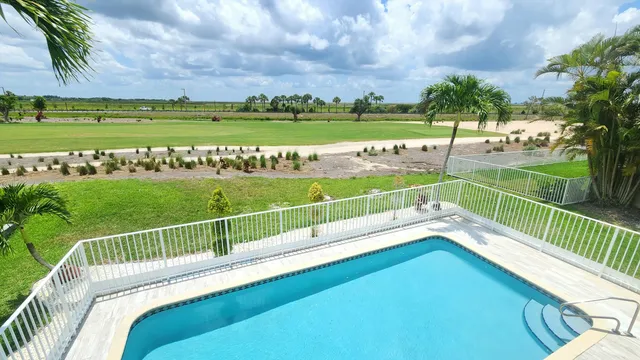a view of a house with a swimming pool and a porch with furniture