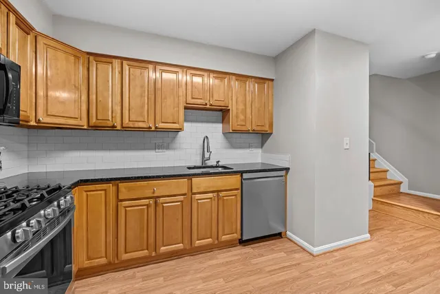 a kitchen with stainless steel appliances granite countertop a stove a sink and dishwasher with wooden cabinets