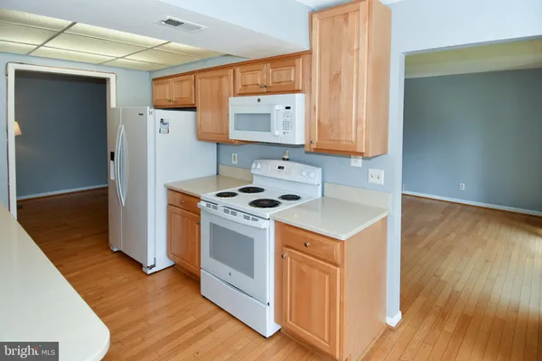 a kitchen with a refrigerator a stove top oven a sink and wooden floor