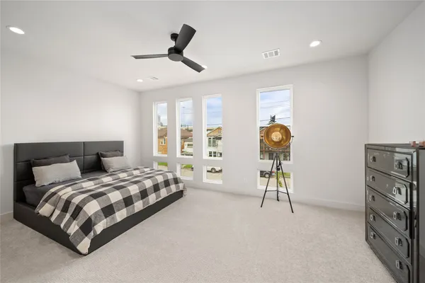 a bedroom with a bed a dresser and a chandelier