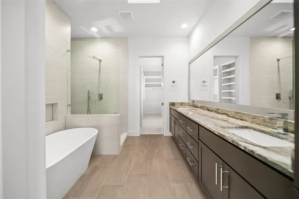a bathroom with a granite countertop double vanity sink a mirror and a bathtub