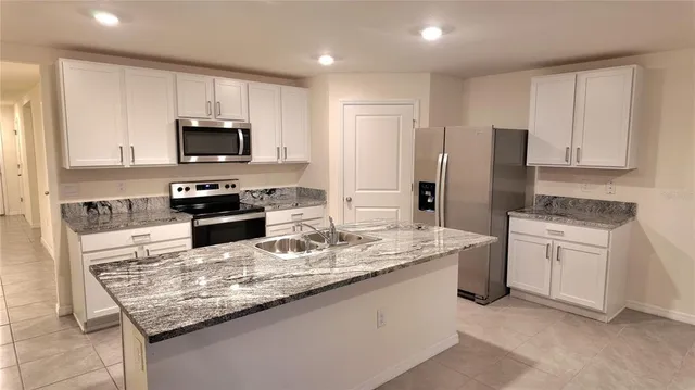 a kitchen with granite countertop a refrigerator and a stove top oven