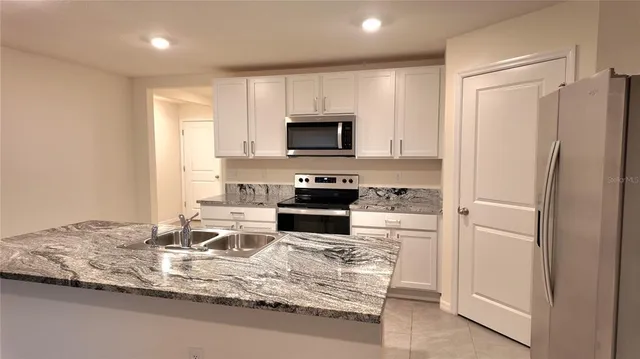 a kitchen with stainless steel appliances granite countertop a sink refrigerator and microwave