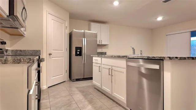 a kitchen with granite countertop a sink a counter top space stainless steel appliances and cabinets