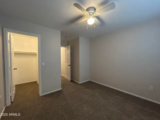an empty room with closet and a chandelier fan
