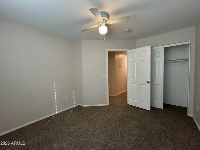 an empty room with closet and a ceiling fan