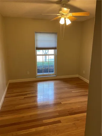 a view of an empty room with window and wooden floor