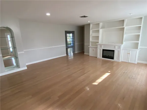 an empty room with wooden floor fireplace and windows