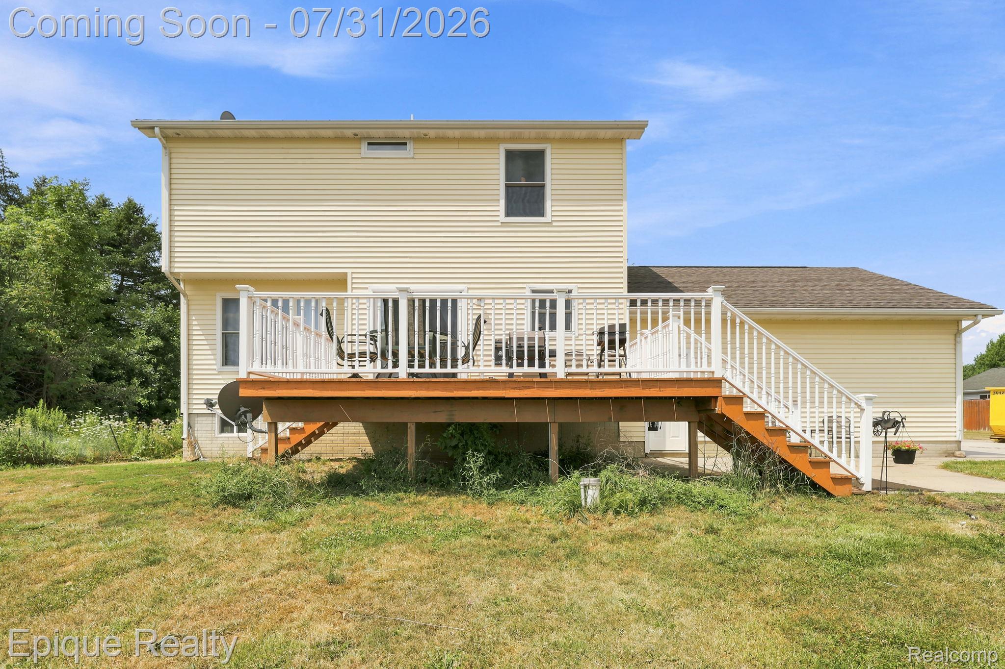 10179 Duffield Road Gaines, MI 48436 - Photo 22 of 30 Rear exterior featuring light yellow siding, a spacious wooden deck with white railings, and a walk-out basement