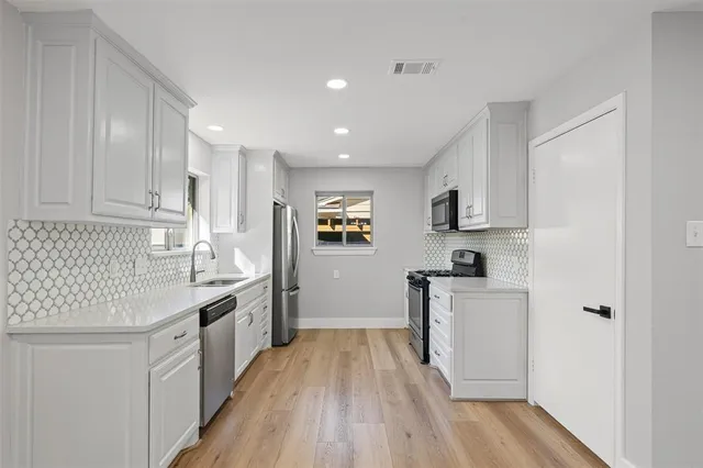 a kitchen with cabinets wooden floor and stainless steel appliances