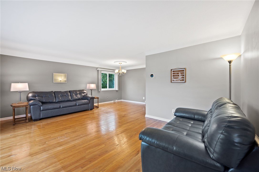 Living room featuring light hardwood floors and a notable chandelier