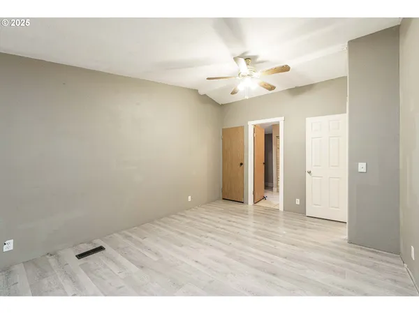 a view of an empty room and chandelier fan