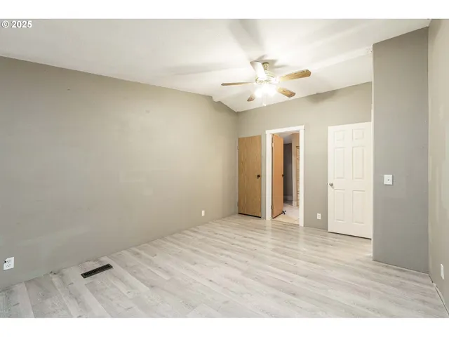 a view of an empty room and chandelier fan