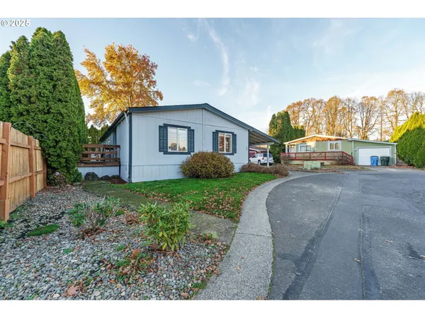 a view of a house with a small yard and a large parking space