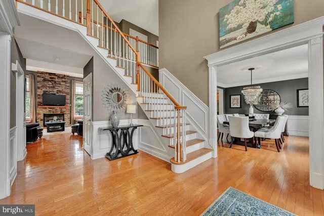 a kitchen with stainless steel appliances granite countertop a refrigerator a sink dishwasher a stove and white cabinets with wooden floor