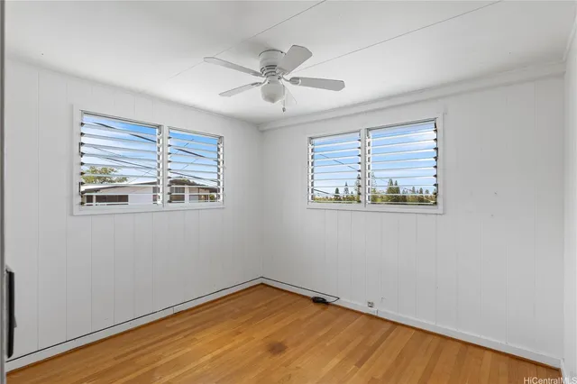 a view of empty room with wooden floor and fan