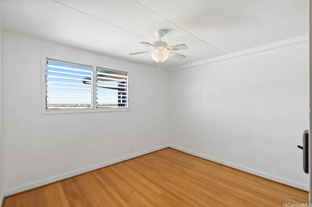 an empty room with wooden floor fan and windows