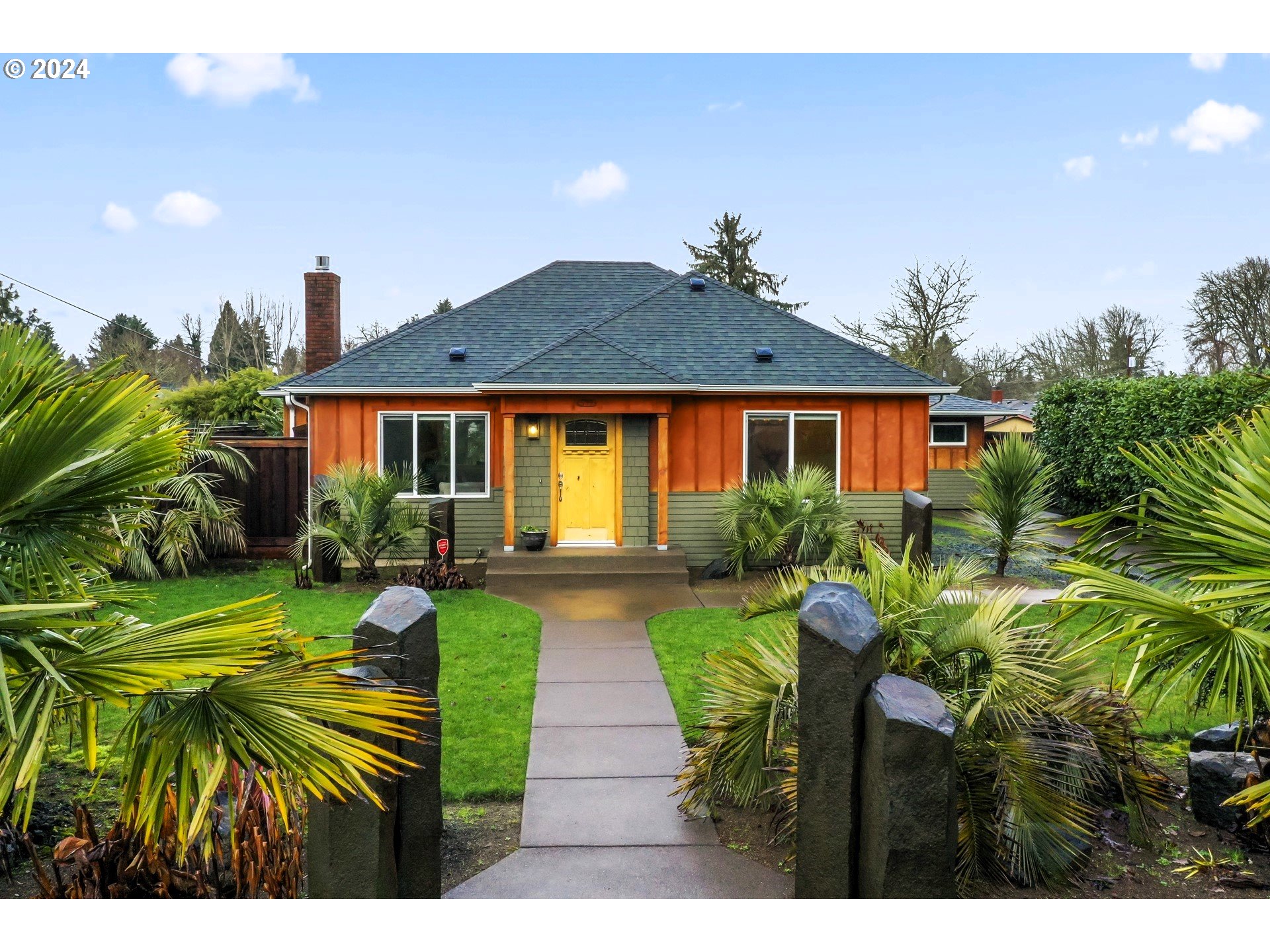 a view of house in front of a big yard with potted plants