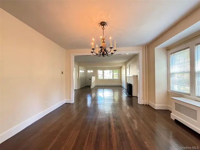 a view of a room with wooden floor chandelier and windows