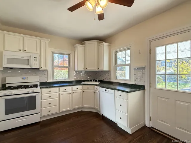 a kitchen with granite countertop white cabinets and white appliances