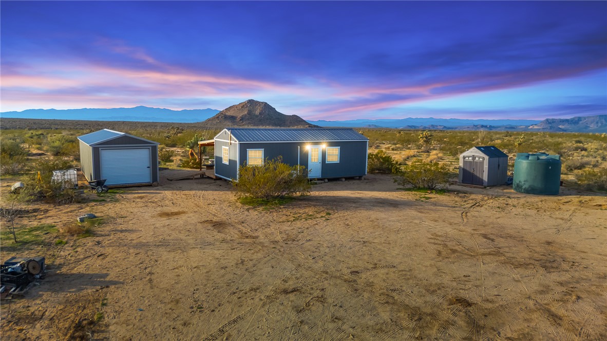 View of front of property featuring a mountain view, a shed, and a metal roof
