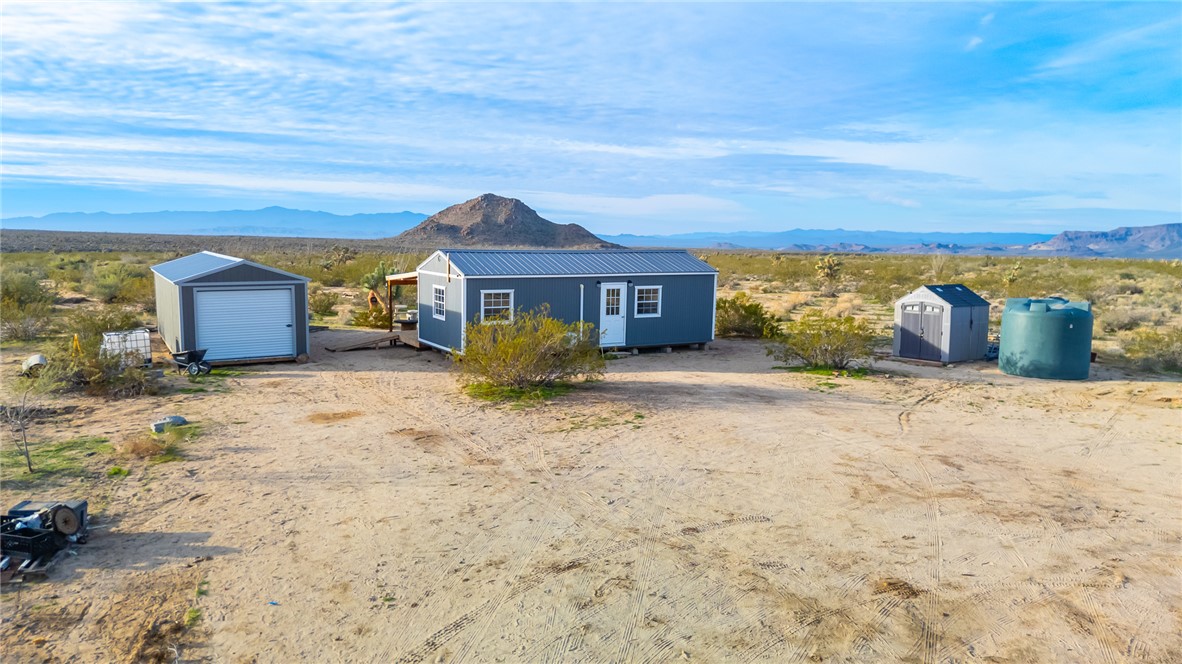 12241 South Robles Road Yucca, AZ 86438 - Photo 2 of 43 View of front of property featuring a storage shed, a mountain view, and a metal roof