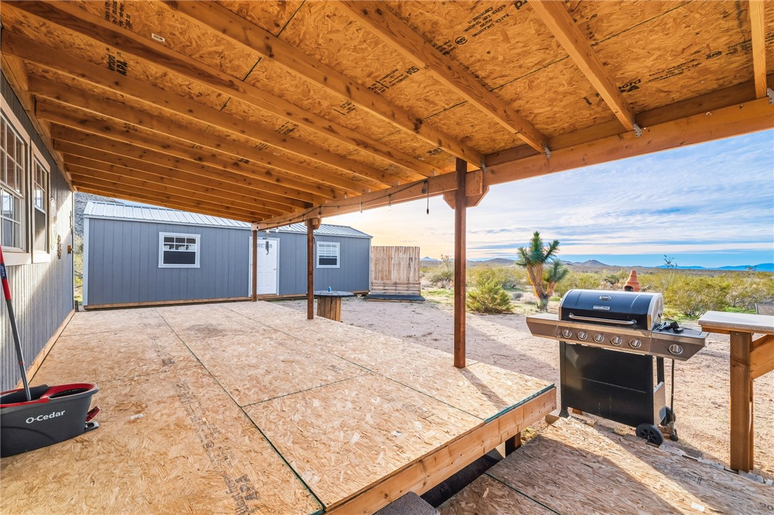12241 South Robles Road Yucca, AZ 86438 - Photo 22 of 43 View of patio with area for grilling, a mountain view, and an outbuilding