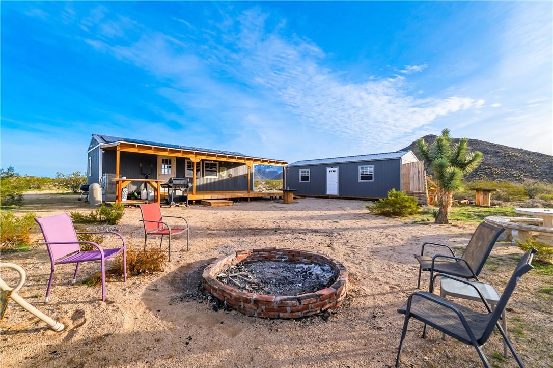 12241 South Robles Road Yucca, AZ 86438 - Photo 27 of 43 Back of property with an outdoor fire pit, a deck, and an outdoor structure