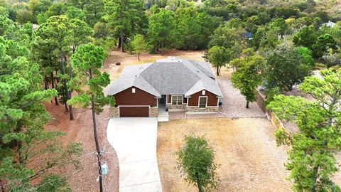 an aerial view of a house with swimming pool and large trees