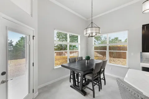 a dining room with furniture large windows and a chandelier