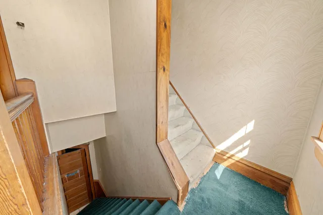 a view of a hallway to a room with window and wooden floor
