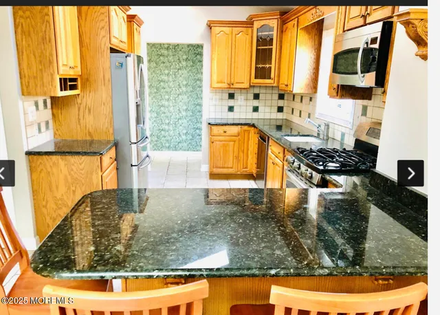 a kitchen with stainless steel appliances kitchen island granite countertop a stove and a sink