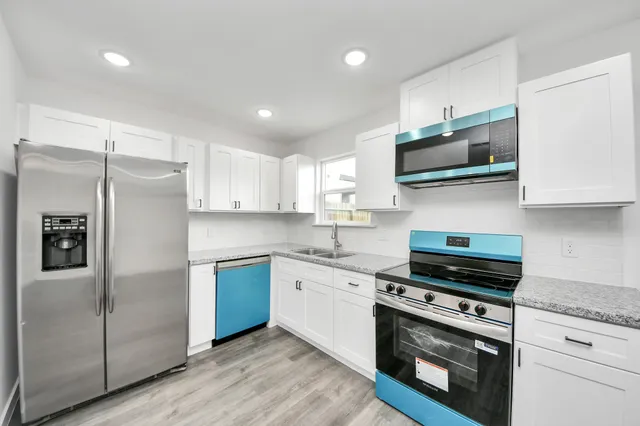 a kitchen with stainless steel appliances granite countertop a stove top oven a sink and a refrigerator