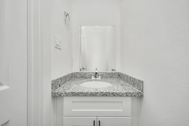 a bathroom with a granite countertop sink and a mirror