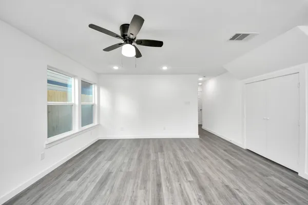 a view of empty room with wooden floor and fan