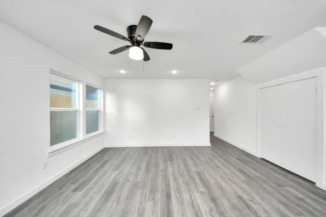 a view of empty room with wooden floor and fan